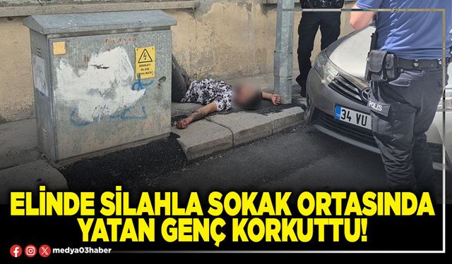 Elinde silahla sokak ortasında yatan genç korkuttu!